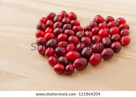 Cranberries in heart shape on wooden board, healthy vitamin food. selective focus
