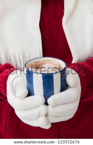 Nothing is better than a classic cup of cocoa on a cold winter day. Close up midriff photo of a woman in warm gloves holding cup of hot chocolate with marshmallows. selective focus.