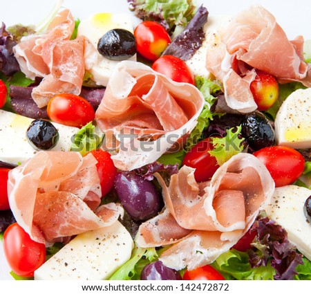 Fresh spring mix salad italian style with prosciutto and mozzarella, seasoned with olive oil and black pepper.