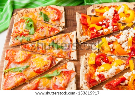 Baked flat bread with bell peppers and feta cheese and also with ham, tomatoes and cheese. selective focus