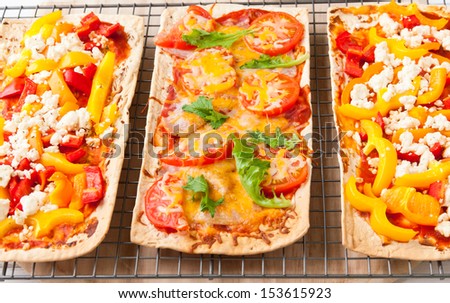Baked flat bread with bell peppers and feta cheese and also with ham, tomatoes and cheese.