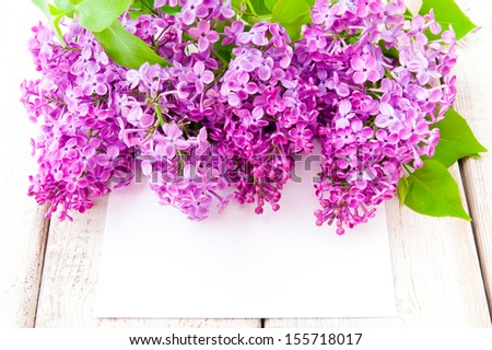Lilac blossoms with card  on wooden table