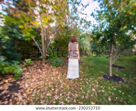 Silhouette of a woman in blurred defocused autumn  garden