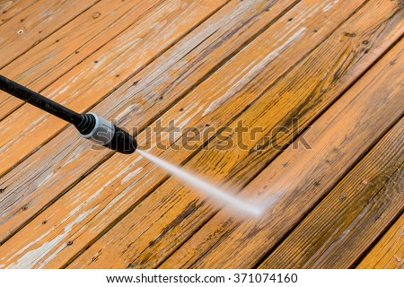 Power washing. Wooden deck floor cleaning with high pressure water jet.
