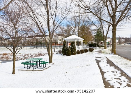 Winter city scene with a picnic table and gazebo at neighborhood recreation area.