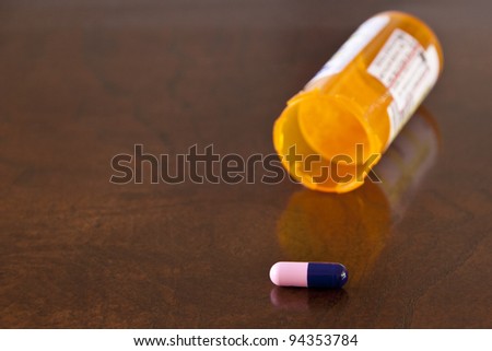 One pill and orange bottle on a table. selective focus