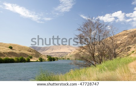 Sandy beach on the Deschutes river bank with desert hills in background