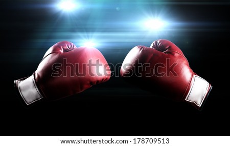 Red boxing gloves with the glow of flashes in the background.