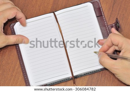Notebook and pen.
Pen in hand on the background of the notebook.