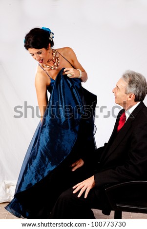 Attractive, mature couple in romantic mood, she is holding her long dress up so he can get a peek underneath.