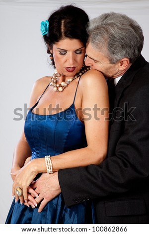 Cute white mature couple in romantic moment with the man kissing the base of her neck, and she is trilling to his loving touch