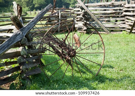 Split rail fence with a hay rake in the sunshine