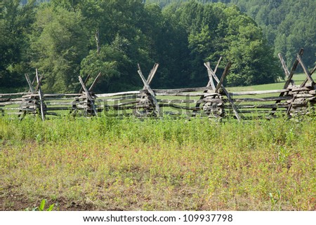 A primitive split rail fence with trees in the background