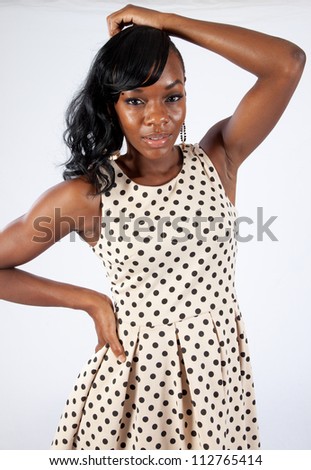 Pretty black woman in a dress, with her hand covering her mouth like she has just heard a happy, surprising secret.