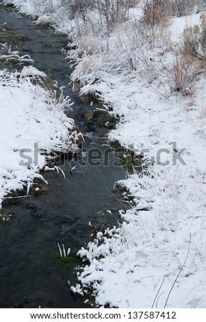 Flowing river with icy, snow banks
