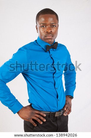 stock-photo-handsome-black-man-in-blue-long-sleeve-shirt-and-bow-tie-his-hands-on-his-hips-looking-at-the-138942026.jpg