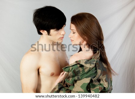 Romantic couple, he is topless and she is wearing a military jacket with nothing underneath, in loving moments