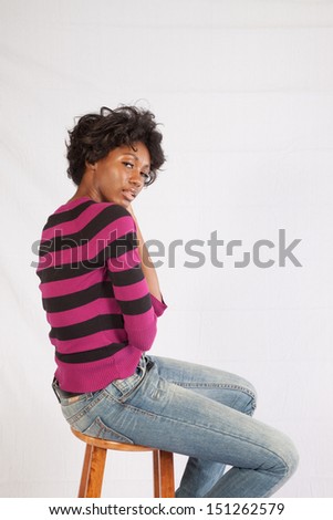 Thoughtful black woman wearing a stripped shirt,  looking at the camera over her shoulder