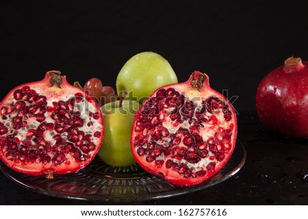 Plate of fruit, with pomegranates, avocados, orange and apples, nourishing food to eat with the pomegranate being cut open