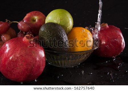 Plate of fruit, with pomegranates, avocados, orange and apples, nourishing food to eat