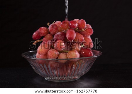 Crystal bowl of purple grapes with water being poured over them