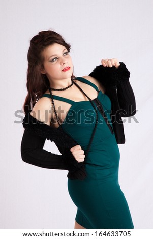 Pretty Caucasian woman in a green dress, taking her black jacket off her shoulders and looking sexy