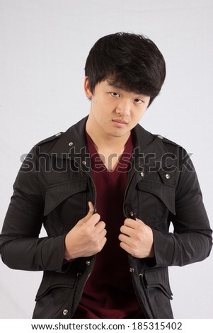 Cute South East Asian teenager in a jean jacket,  looking  at the camera with a serious expression.