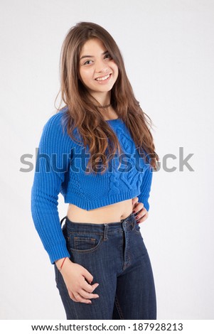 Pretty girl with long hair, in blue blouse and her hand on her hip, looking at the camera with a friendly, happy, smile