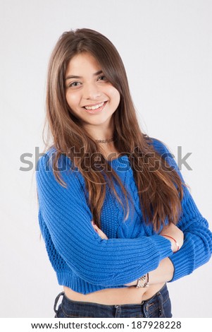 Pretty girl with long hair, in blue blouse and her arms folded, looking at the camera with a friendly, happy, smile