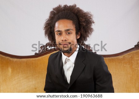 Handsome black man in suit and white shirt, standing and looking at the camera with a pleasing smile
