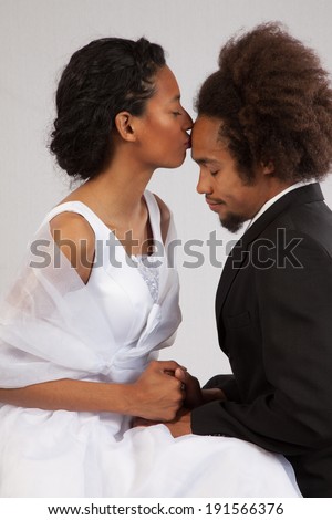 Couple, man and woman, sitting together in a romantic mood, she kissing his forehead