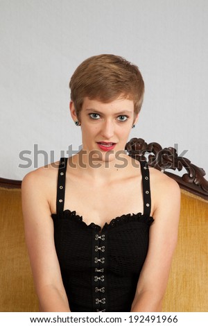 Pretty short haired, Caucasian woman sitting up on a couch with a friendly look for the camera