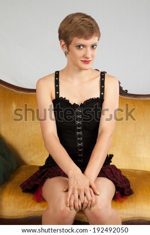 Pretty short haired, Caucasian woman sitting up on a couch with her hands on her knees, and  a friendly look for the camera