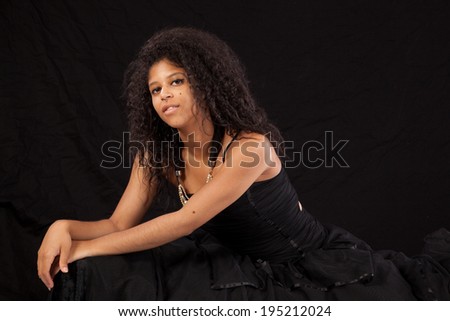 pretty black woman in black dress, smiling at the camera with friendly pleasure