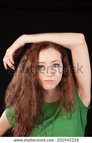 Pretty woman in green blouse, with long hair, with one hand on her head, looking at the camera,