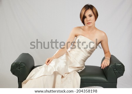 Pretty white woman in formal dress leaning on one arm and looking thoughtfully at the camera