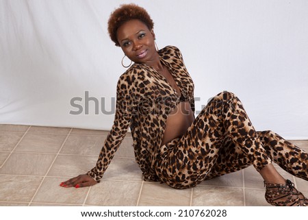 Pretty Black woman in a leopard print outfit, sitting and looking at the camera with a happy smile