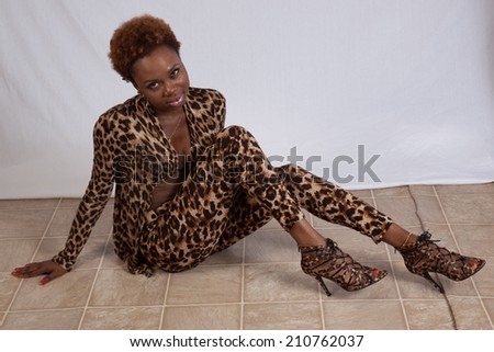 Pretty Black woman in a leopard print outfit, sitting and looking at the camera with a happy smile