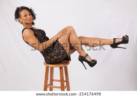 Pretty Black woman balanced on a stool and kicking up her legs