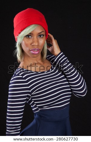 Pretty black woman in stripped blouse and red hat, looking thoughtful with hand on her head