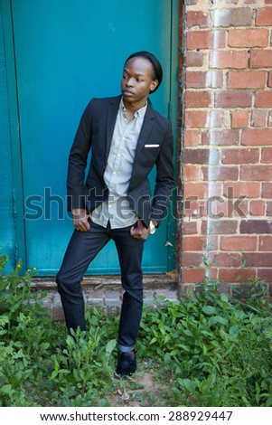 Handsome black man outdoors, in a suit coat, looking thoughtful