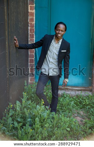 Handsome black man outdoors, in a suit coat, looking thoughtful