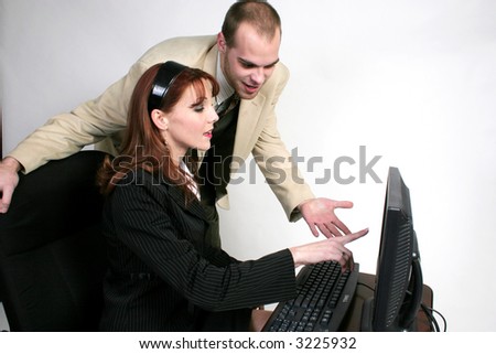 A man is talking to a woman who is working at a computer