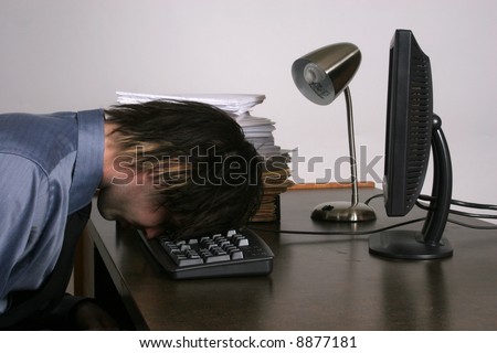 Businessman with head on computer keyboard, tired or frustrated