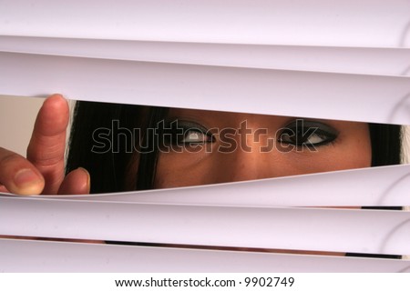 Oriental woman peeking through blinds
