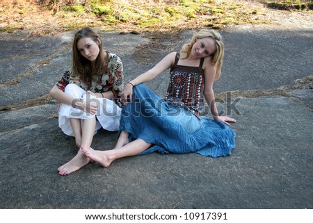 Two lady friends outside sitting on a rock