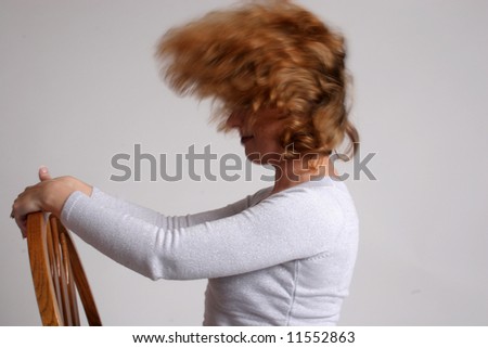 Woman in a chair, slinging her hair back