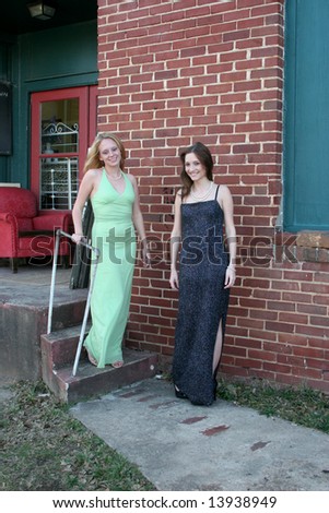 Two women in formal dresses by a loading dock