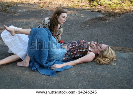 Friends outside, two  women, one laying down, the other leaning over