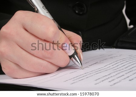 Woman\'s hand holding a pen and writing on a paper